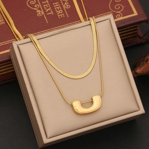 Detail of a gold double-layer necklace with U-shaped pendant on a leather jewelry box