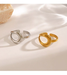 Detailed view of gold and silver hollow teardrop rings on a minimalist stone surface