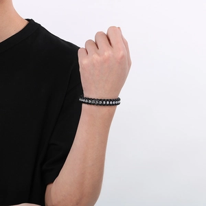 Close-up of braided black leather men's bracelet with silver metal pieces on wrist
