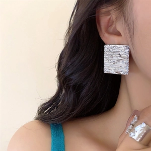 Silver geometric square earrings with pleated texture worn by model for high-end look