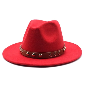 Détail d'un chapeau fedora en laine rouge avec sangle en cuir brun et rivets argentés