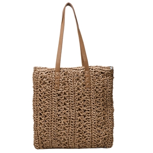 Detail of hand-woven star pattern on brown straw tote bag with thin faux leather handles
