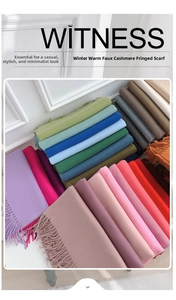 Folded pile of warm faux cashmere winter scarves with tassels in multiple colors