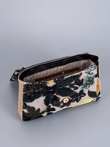 Detailed view of sequin floral embroidery and striped lining inside the woven shoulder bag