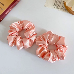 Detail of pink silk satin scrunchies with smooth texture on clean white background