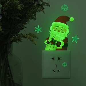 Luminous Santa Claus and snowflake wall stickers glowing green on a wall near a switch
