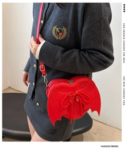 Detail of red heart-shaped crossbody bag with bat wing design and decorative lacing