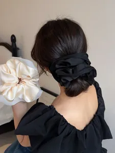 Close-up of premium satin scrunchies in black and beige tied on a hair bun