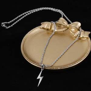 Detail view of silver lightning bolt pendant with twist chain on decorative tray