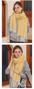 Detailed close-up of yellow knit scarf featuring herringbone texture and tassel fringe edges