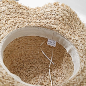 Internal view of raffia sun hat showing woven texture, inner sweatband and adjustable cord