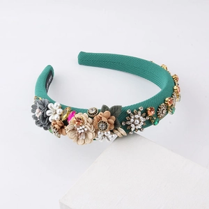 Teal flower headband with pearls and rhinestones on a clean white stone stand