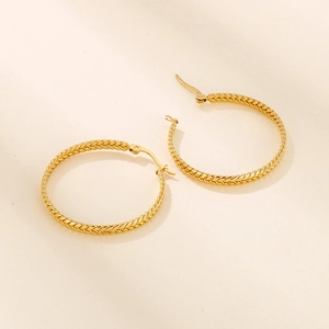 Macro detail of golden twisted rope texture on premium geometric hoop earrings