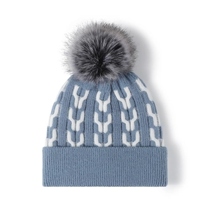 Winter knit beanie in blue with white patterns and a large fluffy grey pompom top