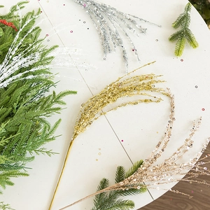 Flat lay of shimmering Christmas glitter twigs and pine needles on white wood background