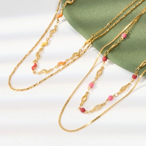 Detailed shot of two golden stainless steel necklaces with colorful enamel drips and beads