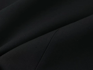 Vue macro du tissu noir montrant le tissage fin et la finition mate de la robe courte