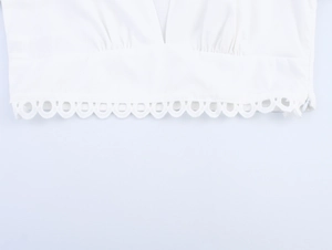 Détail de l'ourlet de la blouse blanche avec dentelle festonnée et plis de confection
