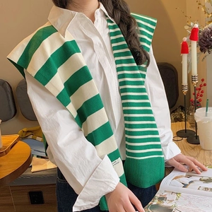 Stylish green and white striped knitted shawl scarf for women in a cafe setting