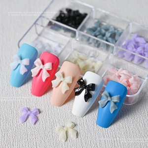 Colorful resin bow nail art accessories set displayed on manicured nail tips