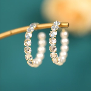 Detail of elegant gold hoop earrings with white pearls and sparkling cubic zirconia stones