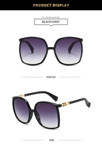 Detail view of large black frame sunglasses with gold metal trim and purple gradient lens