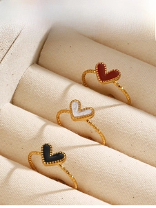 Close-up of three vintage heart rings with red, white, and black enamel on gold bands