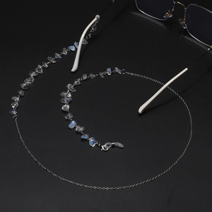 Detail of silver chain eyewear strap with translucent natural stones on a dark background
