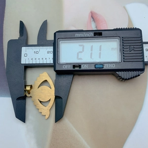 Macro shot showing digital caliper measuring 21.1 mm width of a gold evil eye pendant