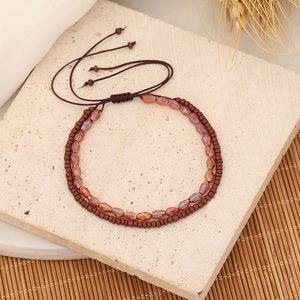 Detail of double-layer woven bracelet with brown beads and crystals on rustic background