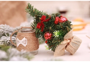 Detail of 20cm mini Christmas tree with red bows and glass bottle with lace tie
