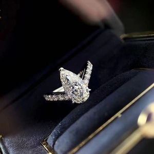 Anello elegante con zircone a goccia e fascia pavé in una scatola di velluto blu