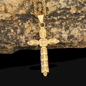 Gros plan d'un collier croix doré avec motifs floraux sur une surface rocheuse sombre