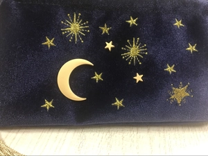 Detail der dunkelblauen Samt-Kosmetiktasche mit goldener Mond- und Sternstickerei