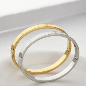Detail of gold and silver stainless steel bangles with crown engraving and grid pattern