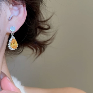 Macro shot of silver drop earrings with yellow teardrop zircon and pavé crystal halo