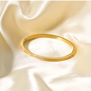 Close-up of 18k gold plated stainless steel bangle with zircons on champagne silk