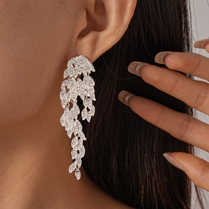 Close-up of sparkling silver leaf dangle earrings featuring pavé rhinestones on model