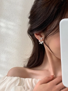 Detail of elegant double butterfly stud earrings with pearlescent finish on model