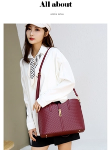 Détail d'un sac cabas tressé bordeaux avec boucle dorée porté par un mannequin