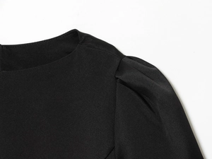 Gros plan macro des manches bouffantes et plis sur l'épaule de la robe noire