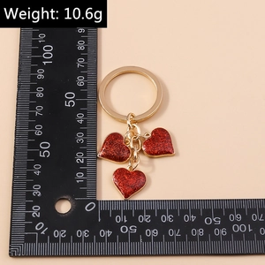 Detailed view of red glitter heart keychain with golden ring and size ruler scale
