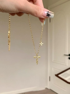 Detail view of 24K gold plated cross necklace with clover charm and textured surface