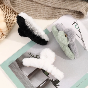 Three plush hair claws in black, white, and grey-green colors shown in a lifestyle set