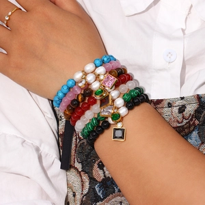 Layered beaded bracelet featuring natural stones, turquoise, pearls, and gold charms