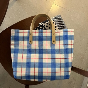 Close-up of blue plaid canvas tote bag with leather handles and copper rivet details