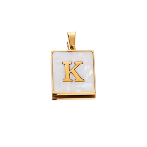 Macro detail of square stainless steel pendant with letter K and white shell inlay