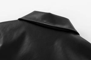 Detailed macro view of the collar and neck stitching on this black faux leather bomber jacket