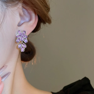 Macro shot of French style violet flower earrings with marquis cut purple gemstones