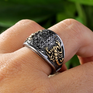 Detailed view of titanium dragon claw ring with gold scorpion relief and black stone inlay